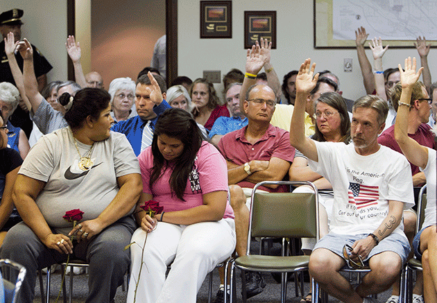 Two women in the front react to a show of hands of Fremont citizens who agree with a speaker who was in favor of implementing a city ordinance against illegal immigrants, in Fremont, Nebraska, July 27, 2010. © AP Photo/Nati Harnik