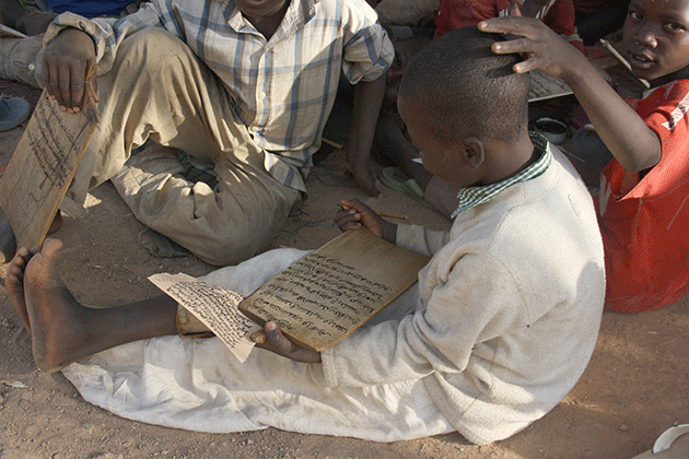A young Almajiri transcribes Koranic verses onto a slate in the street outside Idris Suleiman’s school in Kabala Doki, Kaduna © Caelainn Hogan