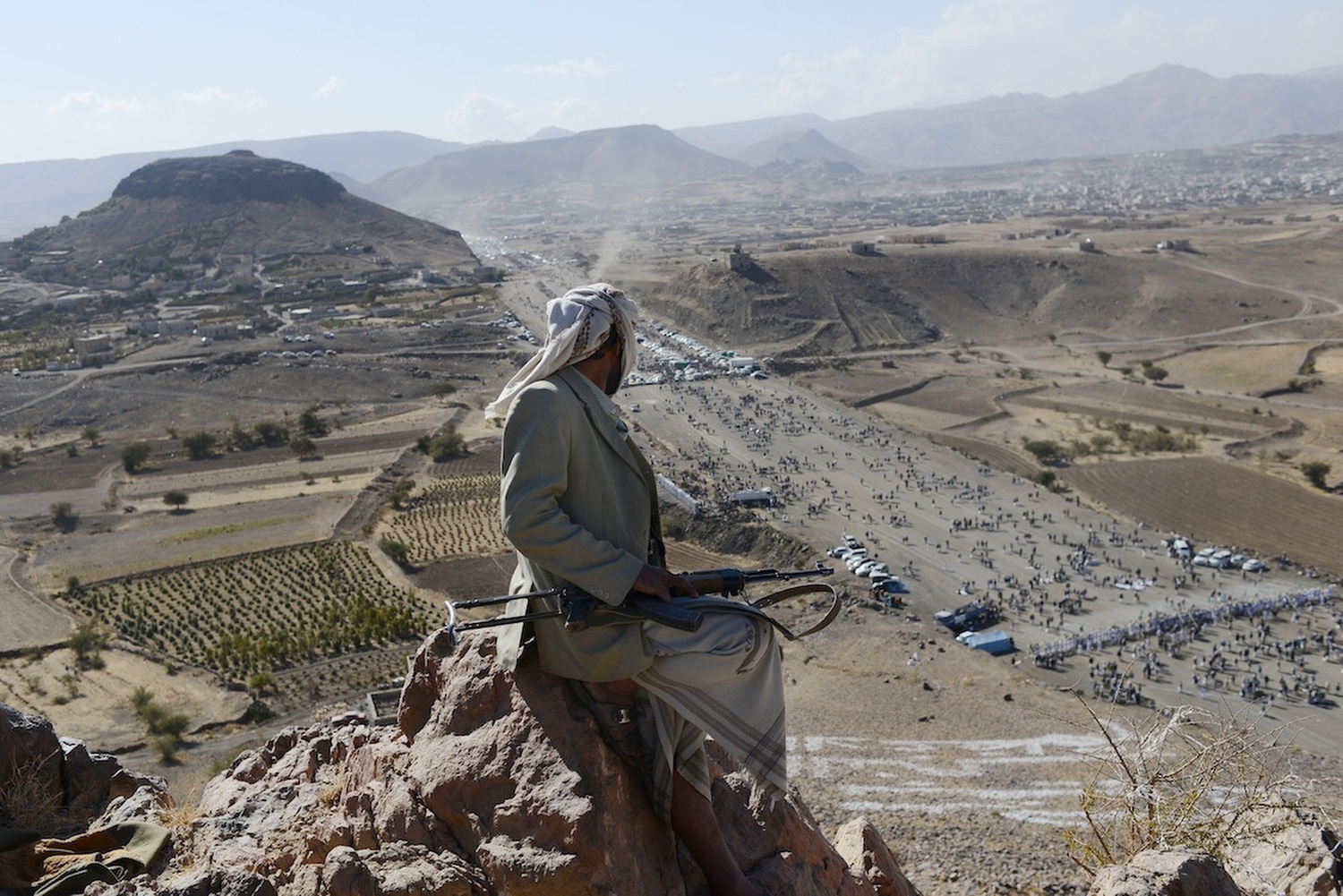A Yemeni tribesman keeps watch from the top of a mountain during a Houthi gathering for Mawlid al Naby, the birthday of the Prophet Mohammad. Thousands of men and women came from around northern Yemen to hear the leader, Abdul Malik al Houthi, address the crowd on politics, religion, and the West. 