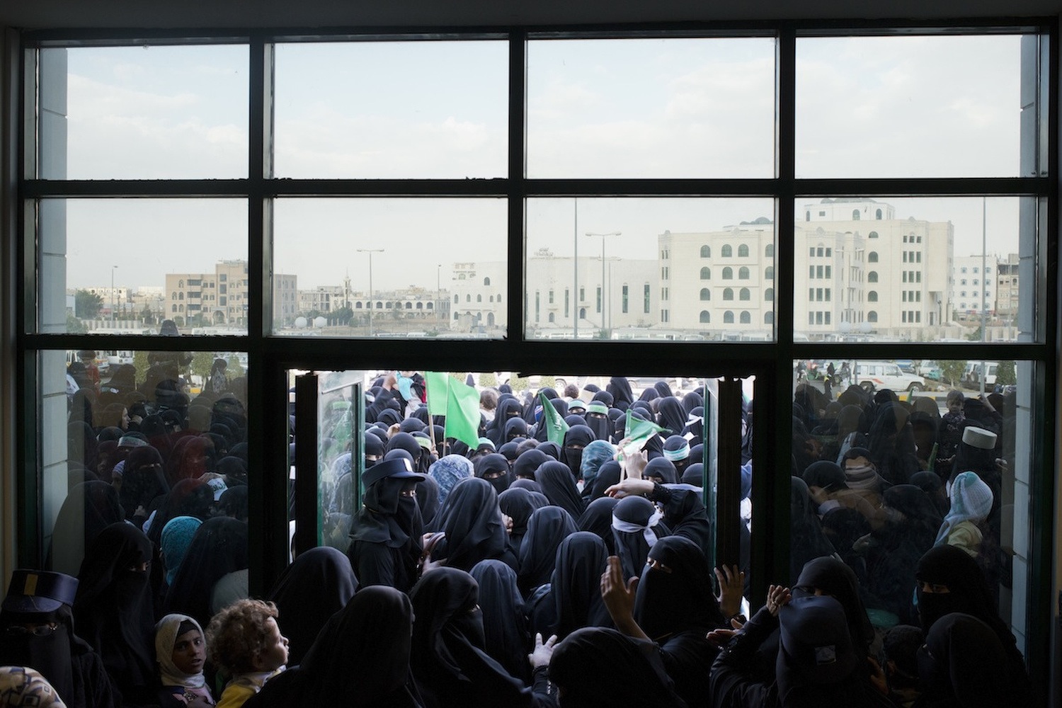 Yemeni women, who are kept separate at public gatherings, squeeze their way through a narrow doorway into a closed stadium for a religious and political rally put on by the Houthis. 