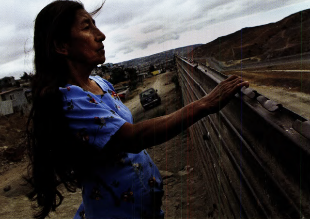 Ubencia Sanchez, from the Chiapas region of Mexico, peers over a border fence in Tijuana, looking into the United States for the first time.