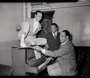 Duke Ellington playing piano, with Charles “Honi” Coles and Billy Strayhorn looking on, at the Stanley Theatre, Pittsburgh, c. 1942–1943 © Charles “Teenie” Harris/Carnegie Museum of Art/Getty Images
