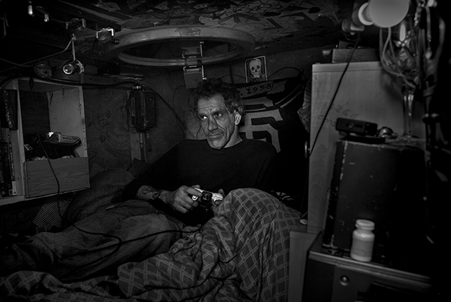 Tate playing a video game in his box, which part of a homeless encampment at the corner of Harrison and Division, February 21, 2016