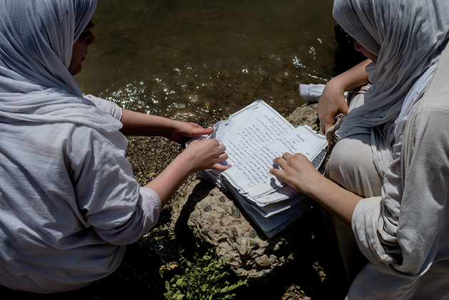 Women read verses from the Mandaean Book of John at the edge of the river