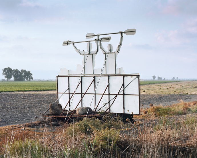 “Transformed Agricultural Machine, Kayak Road Sign Facing Highway 90, Hula Valley,” a photograph by Roei Greenberg