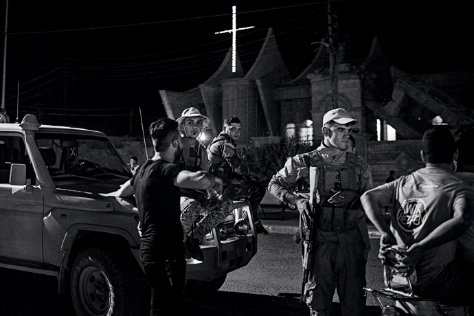 Soldados das Unidades de Proteção da Planície de Nínive guardam a rua principal à noite, em Qaraqosh.