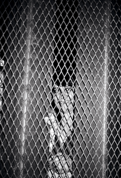 Woman peering in from the Mexican side of the border wall, Nogales, Arizona.